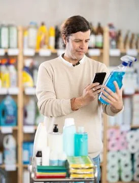 Middle-aged man scanning spray barcode in store Stock Photos