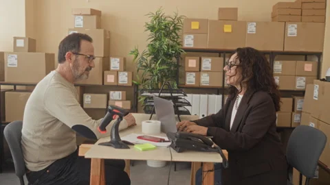 Middle aged man shakes hand with woman across desk over laptop, barcode sca.. 動画素材 337412245