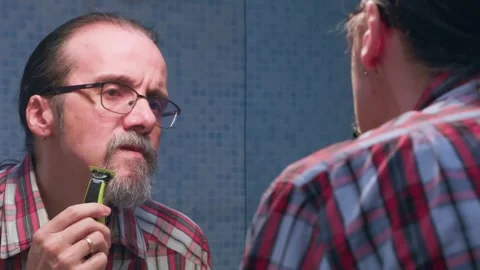 Middle aged man shaves his beard to leave only a mustache Stock Footage 328220193
