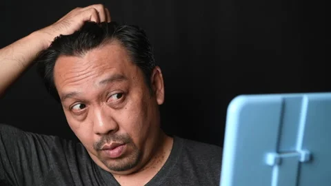 A middle-aged man shines in the mirror and worry about hair loss or hair gray Stock-Footage 172363508