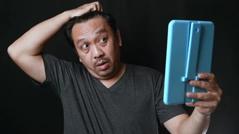 A middle-aged man shines in the mirror and worry about hair loss or hair gray Stock Footage 172363714