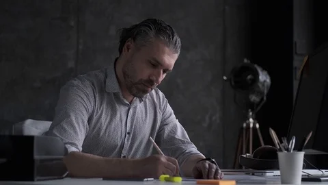 Middle-aged man signs documents while sitting at the table in the office. Stock Footage 108615724