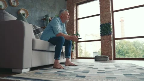 Middle aged man sit couch domestic life watch blockbuster in living room Stock Footage 166624126