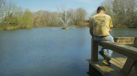 A middle-aged man sits on a dock fishing Stock Footage 22346241