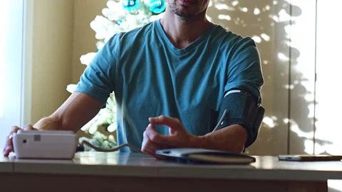 Middle aged man sitting and checking out his blood pressure at home Video stock 328382530