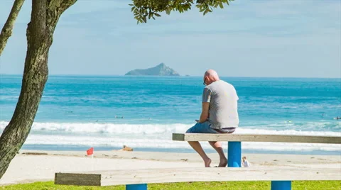 Middle Aged Man Sitting on Bench at Main Beach Tauranga Stock Footage 61106781