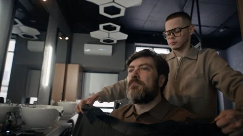 Middle Aged Man Sitting in Chair while Barber Preparing for Haircut Stock Footage 330414152