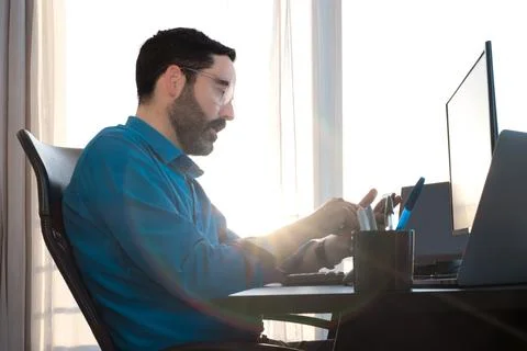 Middle-aged man sitting at desk. Working at home. Typing on smart phone Stock Photos