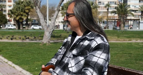 Middle aged man sitting on a park bench Stock Footage 126180810
