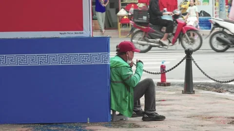 A middle-aged man sitting on the sidewalk with traffic passing. Stock Footage 318142305