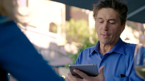 Middle-aged man smiles as he uses his tablet at a restaurant Stock Footage 59742695