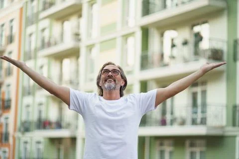 Middle aged man spread his hands in the air praising God standing outdoors Stock Photos