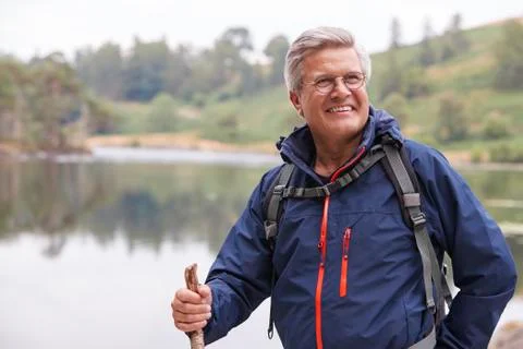 Middle aged man standing by a lake holding a stick smiling, close up, Lake Di Stock Photos