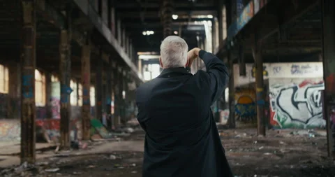 Middle aged man standing in the middle of an abandoned factory Stock Footage 300796831