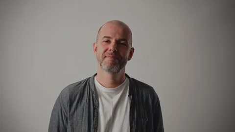 A middle-aged man stands against a white background. He has a kind expression on Stock Footage 297049045