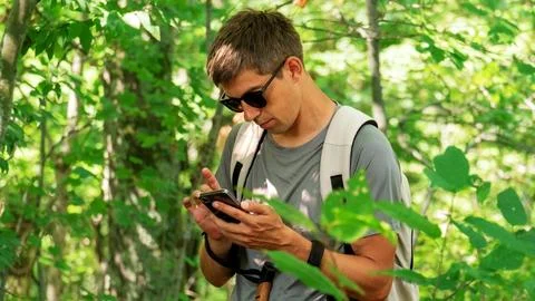 A middle-aged man stands in the forest with Nordic walking sticks and a sma.. Stock Photos
