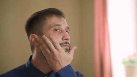 A middle-aged man stands in front of a mirror. Daily face care in the morning 動画素材 168897705