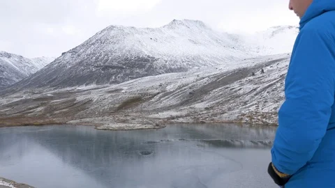 A middle-aged man stands on a high point in the mountains and admires a Stock-Footage 96476747