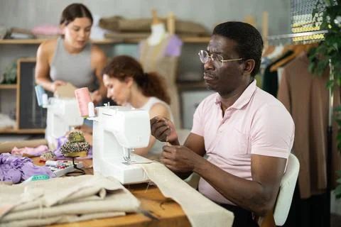 Middle-aged man stitching at machine during sewing class for adults 스톡 사진