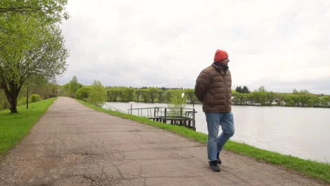 A middle-aged man strolling along the river road Stock Footage 274578596
