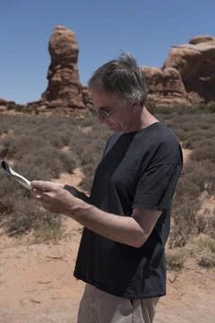 Middle aged man studies map of the trail as he is hiking in southern Utah Stock-Fotos
