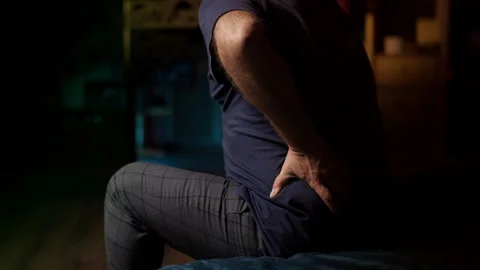 Middle-aged man suffers from back pain while sitting on sofa, spinal disc issue Stock Footage 342520787