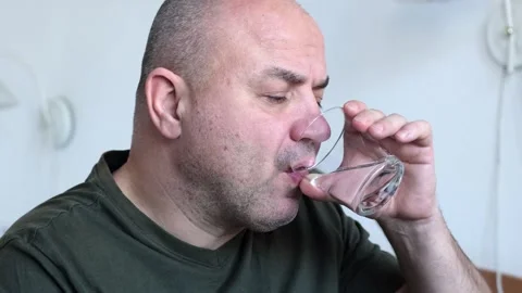 Middle aged man taking pill and drinking water from glass indoors Stock Footage 301893058