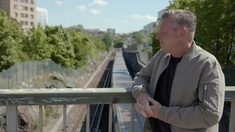 A middle-aged man talking on a bridge over the subway. Vidéo 132563590
