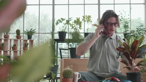 A middle-aged man is talking on phone and he is gardening a tree. 動画素材 140033879