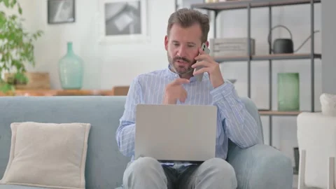 Middle Aged Man Talking on phone with Laptop in Lap Stock Footage 287898329