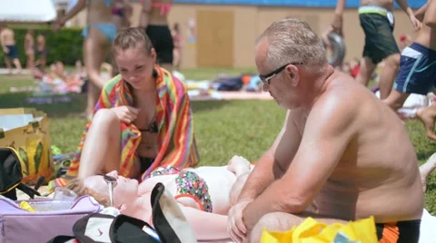 A middle aged man talking to young girls sitting on the grass in the water park Stock Footage 51879164