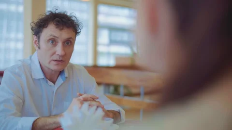 The middle-aged man talks to his family at the restaurant Stock Footage 129520657