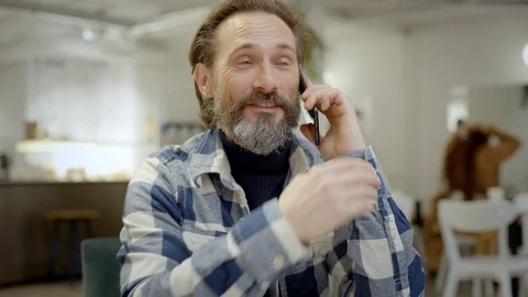 Middle aged man talks on phone in cafe Видео 121579288