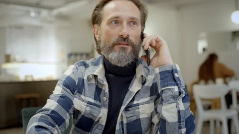 Middle aged man talks on phone in cafe Stock Footage 121582148