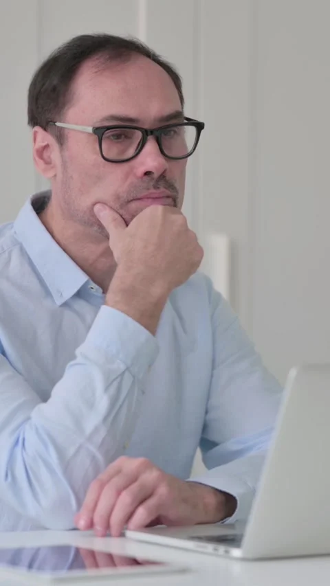 Middle Aged Man Thinking while using Laptop in Office, Vertical Video Stock Footage 339584414