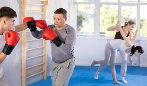 Middle-aged man training boxing with partner during sports classes Stock Photos