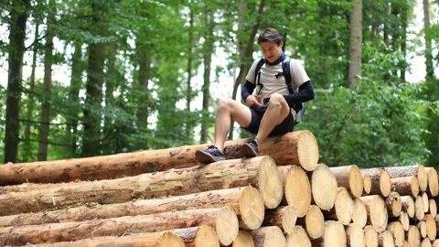 A middle-aged man on a tree stump takes off his backpack in a bad mood Vidéo 252513925