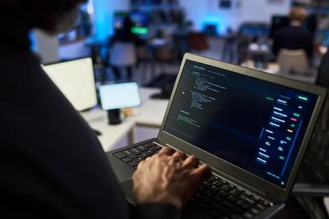 Middle Aged Man Typing Code on Laptop for Cybersecurity Analysis Stock Photos