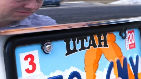 Middle aged man uses screwdriver and bolts to adjust license plate Stock Footage 107928363