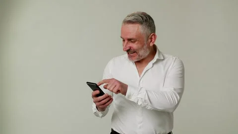 A middle aged man uses a smartphone, extremely happy about winning a large sum Stock Footage 253624853