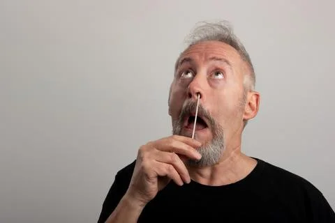 Middle aged man, using the coronavirus antigen rapid self-test, with a cotton Stock Photos