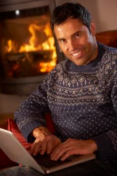 Middle Aged Man Using Laptop Computer By Cosy Log Fire Stock Photos
