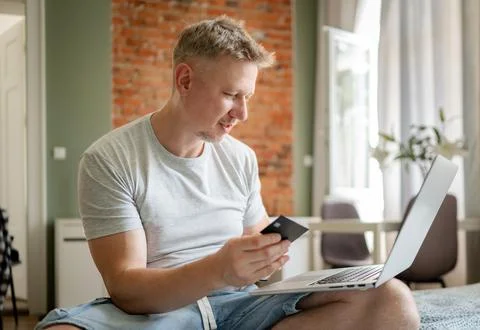 Middle aged man using laptop and credit card on bed in home Stock Photos