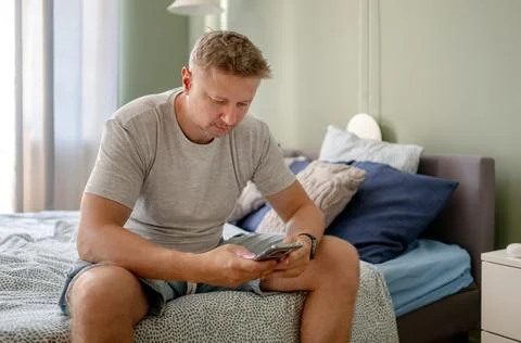 Middle-aged man using phone on bed Stock Photos