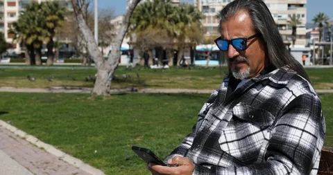 Middle aged man using smart phone at the city park 4 스톡 동영상 126196330