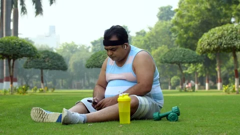 Middle-aged man using smartphone in free time post workout - time pass, fat m... Stock Footage 264034872