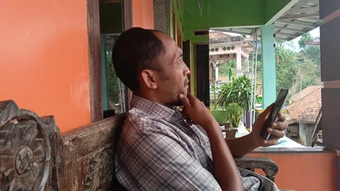 Middle aged man using smartphone on village porch Video stock 316446314