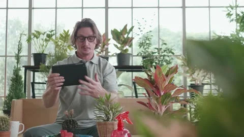 A middle-aged man is using a tablet computer at a video conference with a tree. Stock Footage 143470234