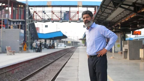 A middle-aged man waiting for the train at the railway station in India - tra... Stock Footage 260803207