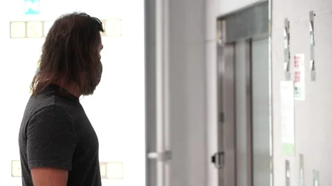 Middle aged man waits to the elevator of the airport terminal wearing a mask  Video stock 136393513